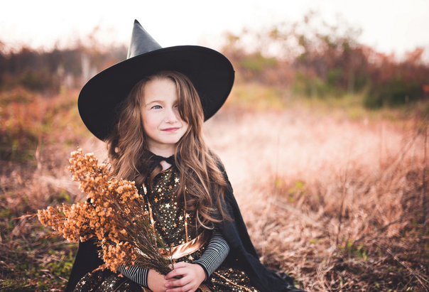 Ein Mädchen kommt im Hexen-Kostüm zur Halloween-Party für Kinder.