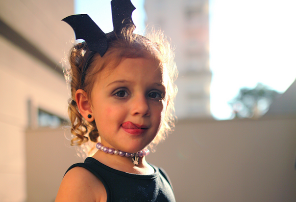 Ein Mädchen im Fledermaus-Kostüm feiert auf einer Halloween-Party für Kinder.