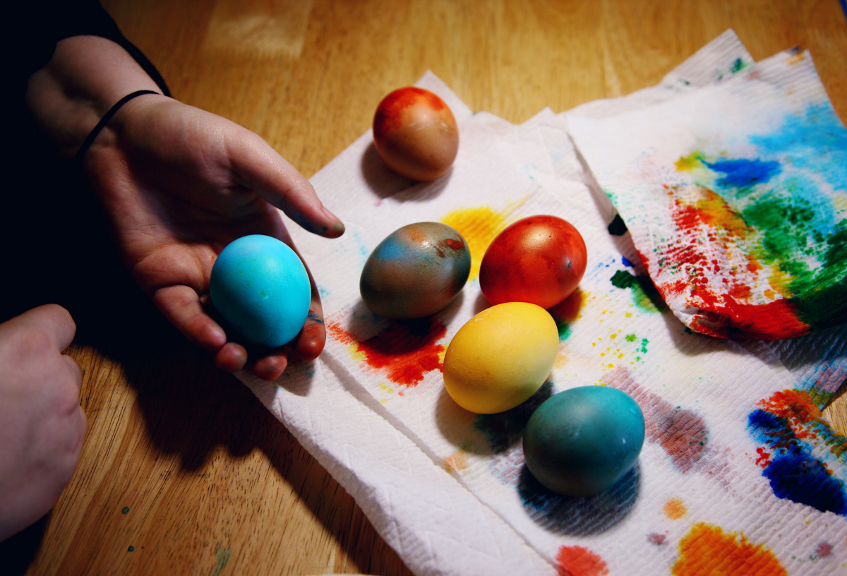 Auf einem mit Küchentüchern bedeckten Holztisch liegen bunt gefärbte Ostereier.