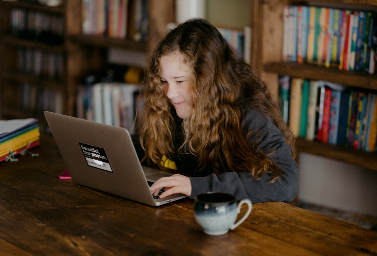 Ein Mädchen sitzt am Laptop und recherchiert ihre Kinderrechte.