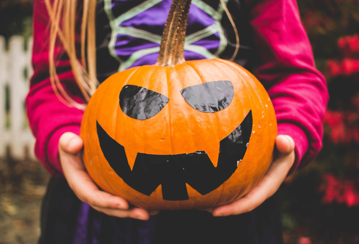 Ein Mädchen auf einer Halloween-Party für Kinder hält einen Kürbis in der Hand.